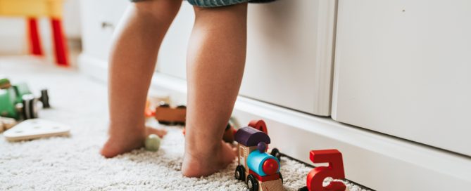 Las piernas de un niño en su habitación con juguetes.