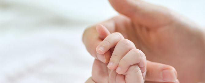 Mano de mujer sostiene la mano de su hijo